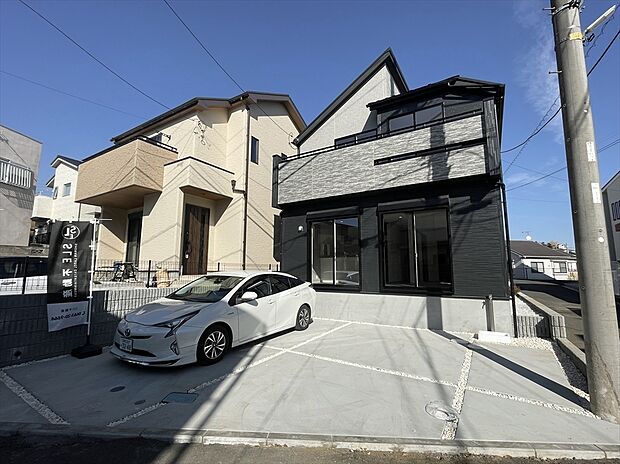 【外観】モダンな外観が目を引く新築戸建て。駐車スペースもしっかり確保し、家族の車も来客時も安心。明るい陽射しに包まれ、毎日を心地よく過ごせる住まいです。