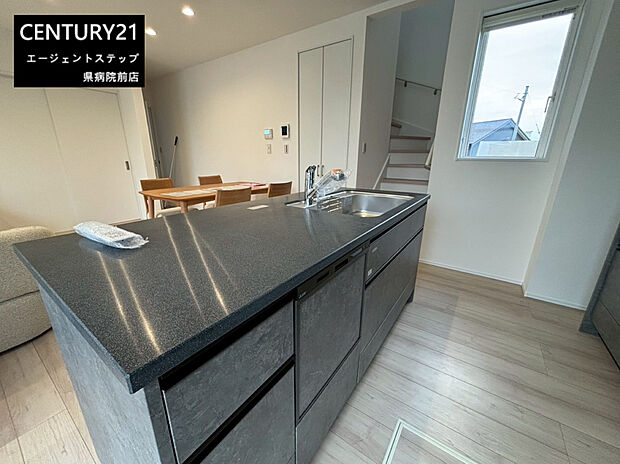 【キッチン】広々としたキッチンカウンターが特徴の空間です。グレーを基調としたデザインが落ち着いた雰囲気を演出します。収納スペースもしっかり確保されておりすっきりとした見た目です。