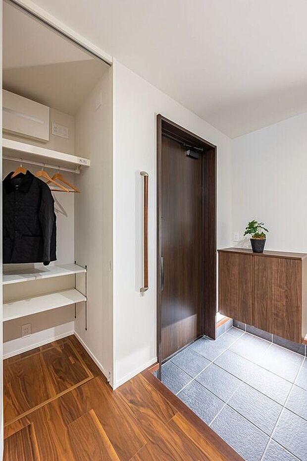 ■玄関 濃いブラウンの木目調と石調タイルが落ち着いた印象をつくる玄関。ホール内にはおでかけクロークを備え、コートやバッグ、外出用品をまとめて収納できます。