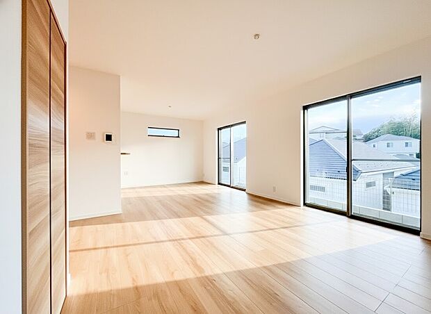 【リビング】2つの大きな掃き出し窓から豊かな陽光が差し込み、お部屋全体を明るく包み込みます。木のぬくもりを感じる柔らかな色調のフローリングが、家族の団らんを優しく演出。