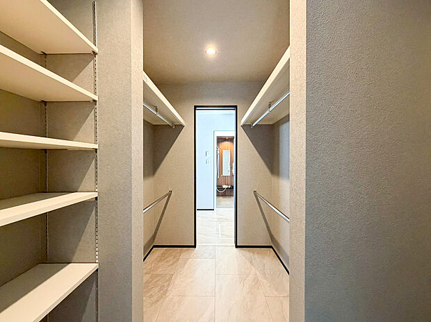 【ファミリークローゼット】約2.6帖の広さを誇る大容量のファミリークロークが、家族の衣類や季節物まで一括管理を可能にします。通路を挟んで両側に枕棚とハンガーパイプを配した機能的な設計で、どこに何があるか一目で分かります。