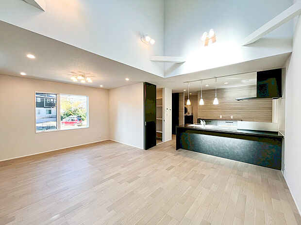 【リビング】デザイン性にこだわった、広々LDK！ 折り上げ天井と複数の窓がもたらす開放感と明るさが魅力です。左のアクセントクロスと右のオープンシェルフが空間にメリハリをつけ、上質で洗練された暮らしを演出。