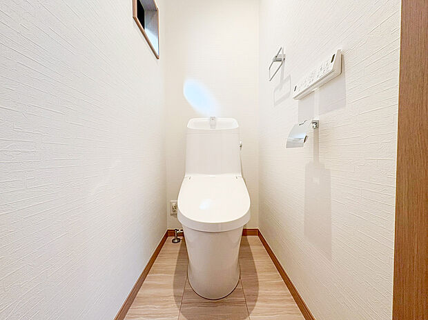【ウォシュレットトイレ】白を基調とした壁紙に木目調のフロアが映える、清潔感と温かみが調和した空間です 。使い勝手の良い手洗い一体型のシャワートイレを採用し、日々の生活を快適にサポートします 。