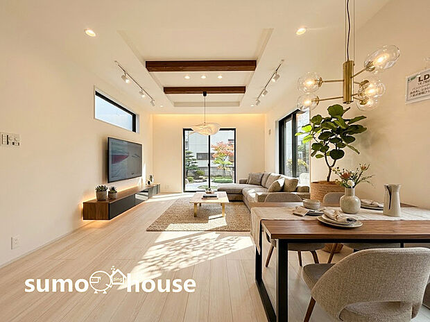 【リビング】天井の折り上げ部分にあしらわれた化粧梁とダウンライトが、空間に奥行きと上質な雰囲気を演出します 。横長のスリット窓は、プライバシーを守りながらも柔らかな光を室内に取り込みます 。(家具等はCGです)