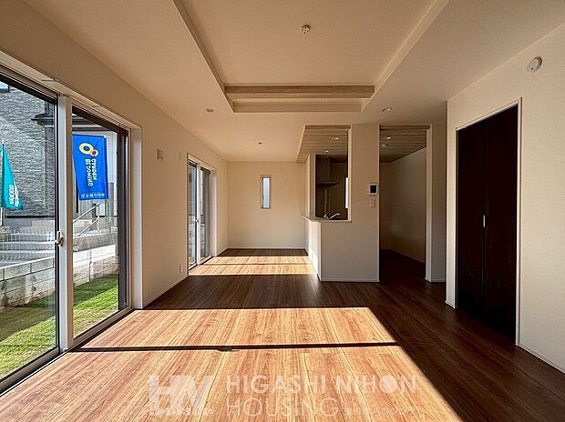 【建物プラン例　（内観写真）】施工例（リビング）光溢れる広々したLDK空間。床や天井の木目使いが空間にリズムを与え、温かみある落ち着いた雰囲気を演出。キッチンからリビングが見渡せる開放的な配置は、家族の繋がりを感じる安心設計