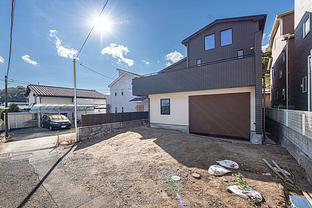 【「ガレージ＋スカイバルコニーの家」】ダークトーンの外壁が空に映えるスタイリッシュな邸宅。広大な敷地と並列駐車可能なカースペースが、ゆとりある暮らしを叶えます。