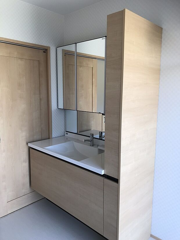 【木目のやさしさが映える洗面台参考画像（PENTHOUSE）】木目調の扉がやさしい雰囲気を演出する洗面台。広々としたボウルとカウンターで使い勝手も良く、朝の身支度や家事もスムーズに行えます。三面鏡裏には収納スペースを確保しており、洗面まわりをすっきり整理できるのも魅力。シンプルで清潔感のあるデザインで、日々の暮らしに心地よさをプラスします。機能性とデザイン性を兼ね備えた洗面設備です。