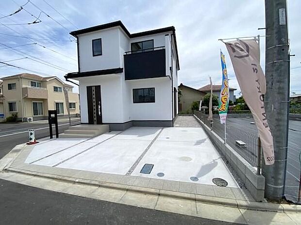 【現地外観写真】15号棟　角地は道路に面する幅が広いため、バック駐車や切り返しが驚くほどスムーズ。左右の見通しも良く、お子様の飛び出しなどにも気づきやすい安心設計です。毎日の送り迎えやお買い物も、軽やかにこなせます。