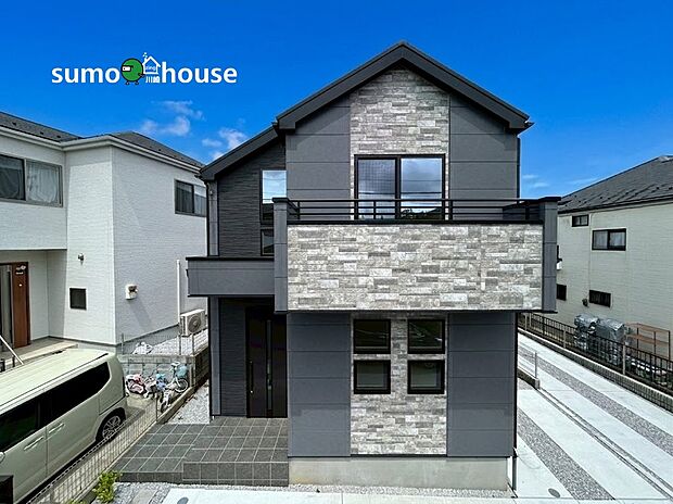 三角屋根のシルエットがお洒落なスタイリッシュ邸宅。落ち着いたグレーの外壁に、高級感漂う石目調のアクセントが美しく映えます。玄関まわりにはアプローチ階段が設けられ、洗練された佇まいを演出しています。