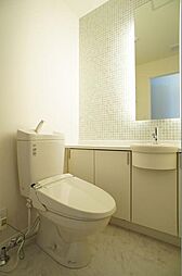 【暖房洗浄便座】3階フロアのトイレです。壁付タイプのリモコンでスッキリとしたデザインです。壁にタイルを貼り、便利な手洗いカウンター・可動棚・洗濯機スペースもあります。