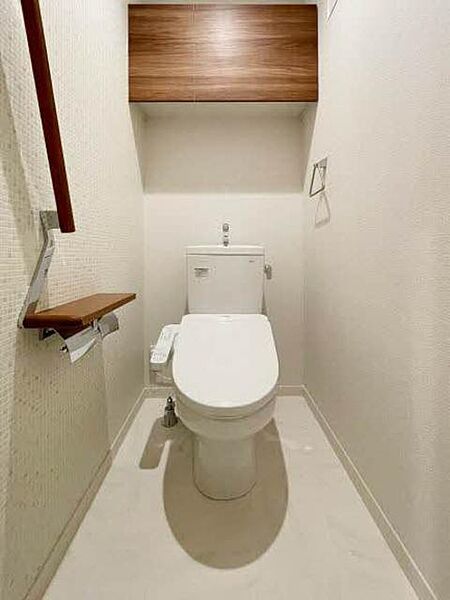 画像10:【トイレ】タイル調のアクセント壁がおしゃれなトイレ。上部吊戸棚、手摺、小物置きに使えるペーパーフォルダー天板があり、機能的にも充実しています。