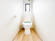 白を基調とした、清潔感あふれるトイレ空間。スリット窓から自然光が差し込み、明るく爽やかな印象を与えます。温水洗浄便座付きで、毎日を快適に過ごせる機能性もしっかりと備わっています。