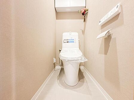 落ち着いたトーンのアクセントクロスが、安らぎの空間を演出するトイレ。温水洗浄便座付きで、上部には備品をすっきりと収納できる吊戸棚を備えています。清潔感があり、細部までこだわりが感じられる設計です。