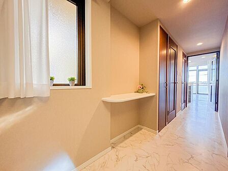 大理石調のフロアが奥まで続く、高級感溢れる廊下。便利なカウンター棚が設置されており、お気に入りのインテリアや季節の花を飾って空間を彩れます。