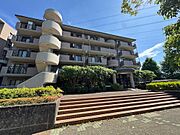 青空に映えるモダンな外観と、特徴的な螺旋階段が目を引くマンションです。豊かな植栽に囲まれ、お子様との毎日を彩る安心感のある住まい。