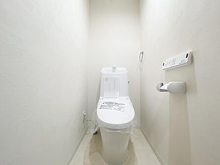 手洗い一体型の清潔感あふれるトイレ。壁付けリモコン・トイレットペーパーホルダー付きで快適。