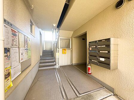 集合ポストや掲示板が整然と配置されたエントランス。ベビーカーも通りやすい通路と階段があり、お子様連れの移動もスムーズです。
