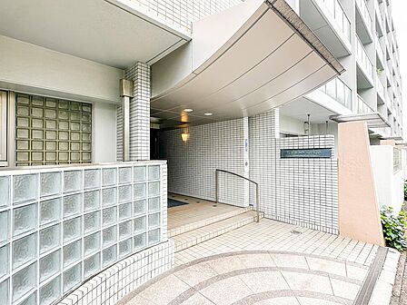 「明るいホワイトタイル張りの上品なエントランス」ガラスブロックがモダンなアクセントを添える洗練されたアプローチ。掃除が行き届いた綺麗な共用部から、日頃の管理体制の良さがしっかり窺えます。