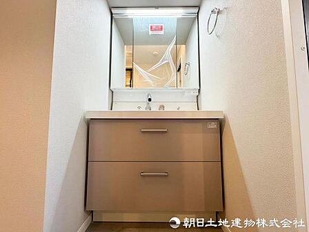 【洗面化粧台】 三面鏡裏収納付き洗面化粧台。身支度用品をすっきり収納でき、脱衣スペースも広く確保された快適な洗面空間です。