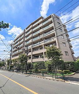外観：街並みに調和する落ち着いた佇まいのマンション。前面道路は整っており、周囲の緑も豊かな住環境です。