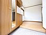 玄関：【現地内観写真】玄関内部から。大きなコの字型のシューズボックスが設置されており、お履き物が多い方でも安心です。