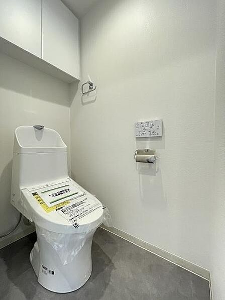 白で統一された清潔感のあるトイレ!上部に扉付きの収納があります。日用品をすっきりストックできます!