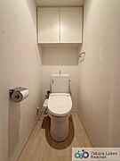 ウォシュレット機能付きのトイレ。上部には吊戸棚があるので、トイレットペーパーのストックや清掃道具等を収納するのに便利です。