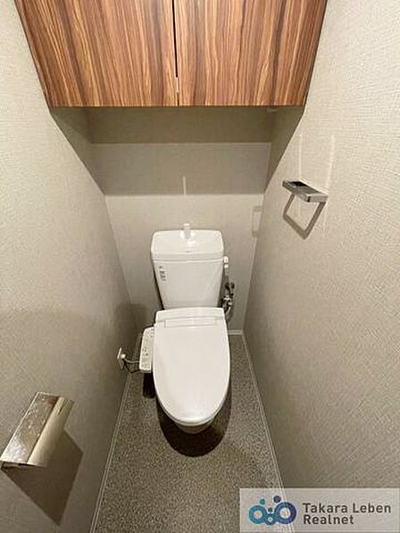 ウォシュレット機能付きのトイレ。上部には吊戸棚があるため備品等を収納するのに便利です。