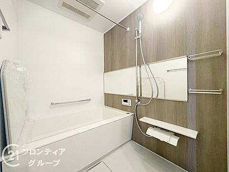 木目調の壁が落ち着いた雰囲気を演出する、ゆとりある広さのバスルームです。手すりの設置や使い勝手の良いシャワーなど、細部までこだわり抜いた機能性が日々の疲れを優しく癒やすリラックスタイムを実現します