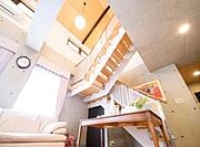 大きな吹き抜けから優しい光が降り注ぐリビング。天井高と窓の配置により、時間帯によって表情が変わる心地よい空間です。