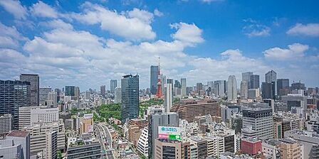 バルコニーからは、周辺に建ち並ぶ多様なビル群や緑豊かな敷地、中央に位置する特徴的なタワーなど、広大な都市の街並みがどこまでも広がる景色を見渡すことができます。