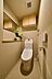 トイレ：温水洗浄機能付きの便座や壁掛けリモコンを備えたトイレには、上部に木目調扉の吊戸棚がありストック品を整理できるほか、側面には横長の鏡が配置された棚付きカウンターが設置されております。