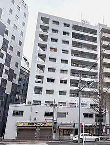 外観:白を基調としたシンプルな外壁が特徴的な建物で、低層部には店舗スペースが設けられており、上層階には規則的に開口部や手すり付きのバルコニーが配置された構造となっています。 外観:白を基調としたシンプルな外壁が特徴的な建物で、低層部には店舗スペースが設けられており、上層階には規則的に開口部や手すり付きのバルコニーが配置された構造となっています。