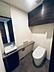 トイレ：タンクレストイレを採用した清潔感のあるトイレ空間には、鏡や下部収納が付いた手洗いボウルや石目調のカウンター、上部にはペーパーなどの保管に便利な木目調の吊戸棚が備えられています。