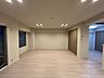 リビング/ダイニング：ナチュラルな質感の木目調フローリングが施された居室には、天井に埋め込み式のダウンライトが複数配されており、壁面には木目デザインの大型クローゼット収納が設置されています。