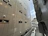 その他：バルコニー側からは、縦ラインの入った外壁パネルや小窓が並ぶ隣接建物が見え、周囲にはビルやマンション等の建物が整然と立ち並んでいます。