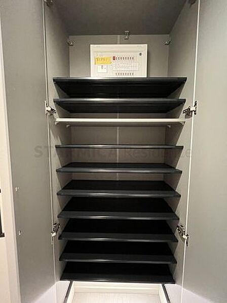 大容量の下足収納を備え、足元から明るい照明が照らす玄関。