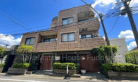 落ち着いた色合いのタイル張り外観。植栽も配置された住まいです。