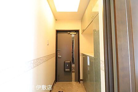 【玄関】落ち着いた照明が家族を温かく迎える玄関。機能的な壁面収納により、すっきりとした空間を維持できます