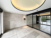 円形の間接照明が印象的なホテルライクなエントランスロビー。石張り壁×大判タイル床の洗練されたデザインが、帰宅するたびに非日常を演出します。