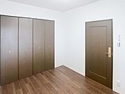 広々とした収納が魅力の洋室。落ち着いた色合いのドアとフローリングが、モダンな雰囲気です。