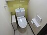 トイレ：タンク一体型トイレは省スペースで、手洗いも可能です。壁面には収納とペーパーホルダーが備わり、機能的な空間です。