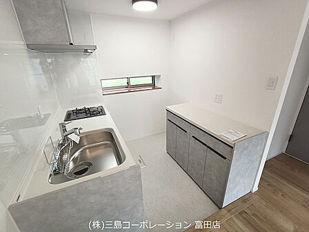 機能的なガスコンロとシンクを配したキッチン。調理器具の収納に便利なキャビネットもございます。