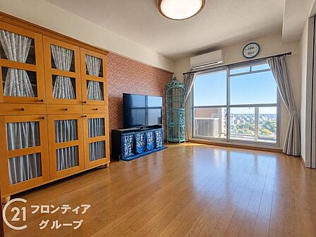 大きな窓から心地よい自然光がたっぷりと差し込む明るい空間ですね！温かみのある木目調のフローリングと美しいアクセントクロスが調和し、家族みんながゆったりとくつろげる理想的な団らんのひとときを演出します