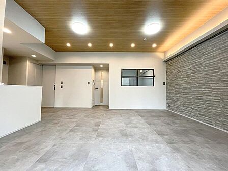 木目の天井とグレーのタイル調の床材がスタイリッシュで上質なリビング空間を演出します。