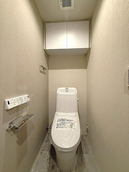 ウォシュレット一体型のトイレ。吊戸棚があり足元の空間もすっきりとお使いいただけます。