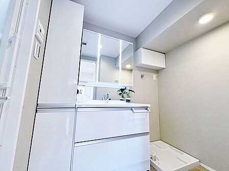 洗濯機置場はもちろん洗面台の隣に。収納もあり、スッキリとした空間。