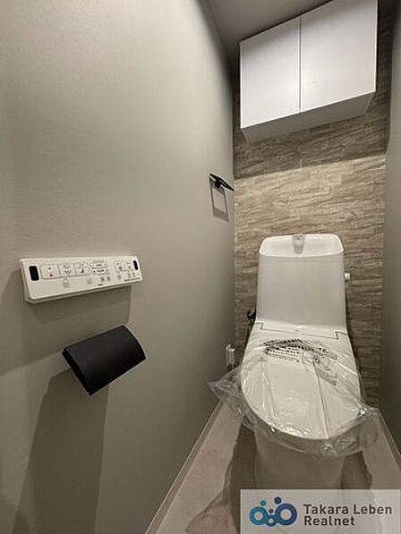 ウォシュレット機能付きのトイレは壁掛けリモコンの上位グレードを採用。便座がスッキリした印象となり、限られた空間を広く見せる効果があります。