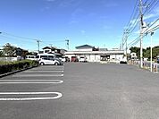 広々とした駐車場と、穏やかな青空が心地よい空間を演出します。（110m）