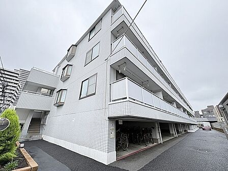 洗練された白いタイル貼りの外観が街並みに調和し、穏やかな日常を予感させる佇まい